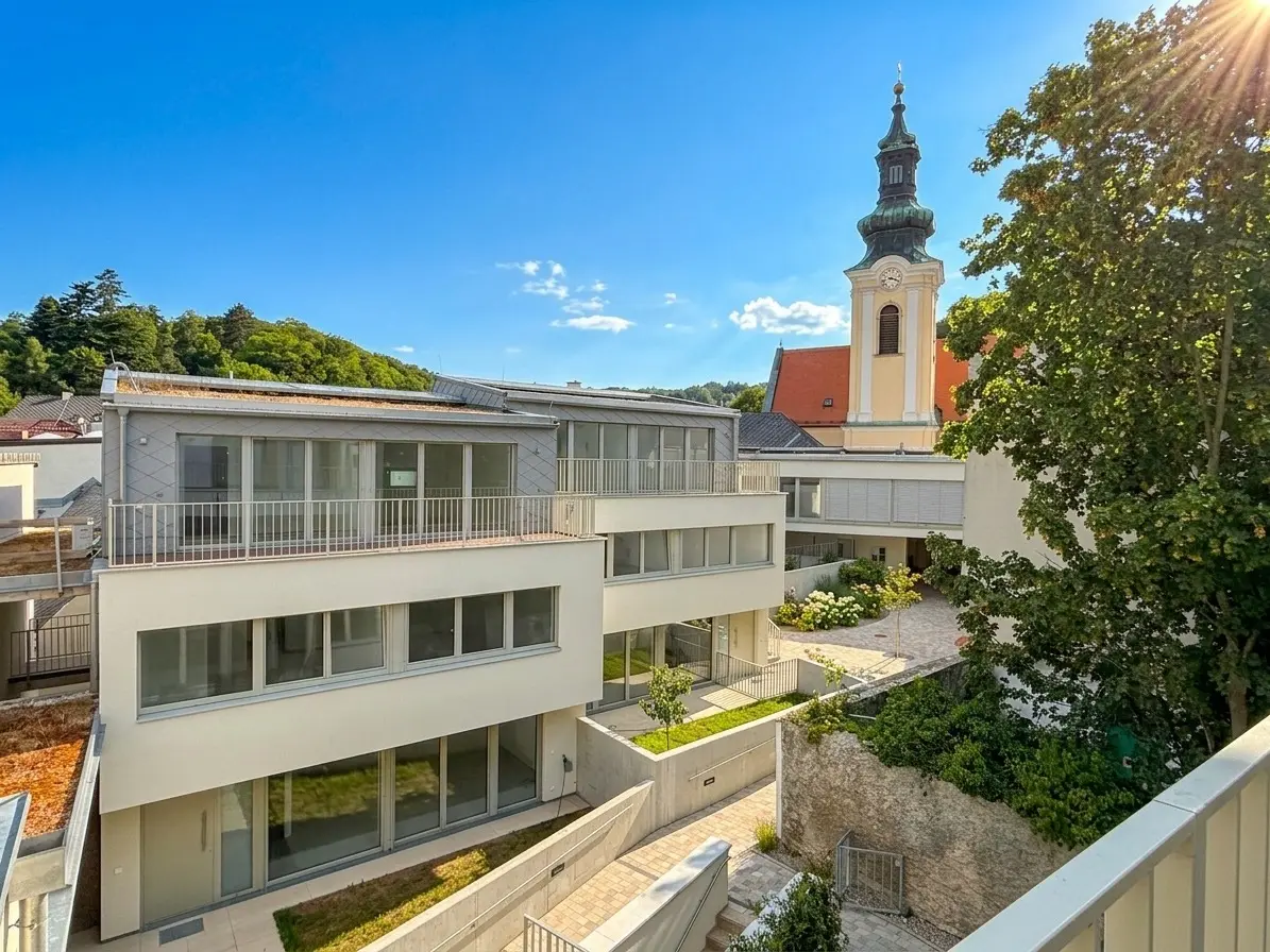 Wohnanlage mit begrüntem Innenhof und Weidlinger Kirche